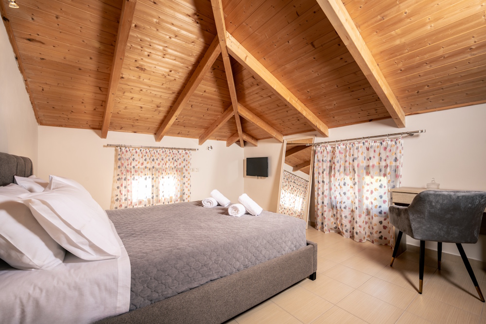 Bedroom with double bed, wooden ceiling, and desk at Kristallia Villa in Zakynthos.